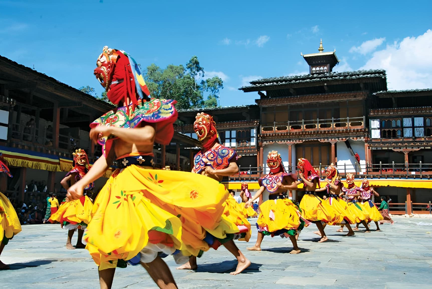 Mask dancers mid-performance in the courtyard of Tashi Chhodzong during Thimphu Tshechu