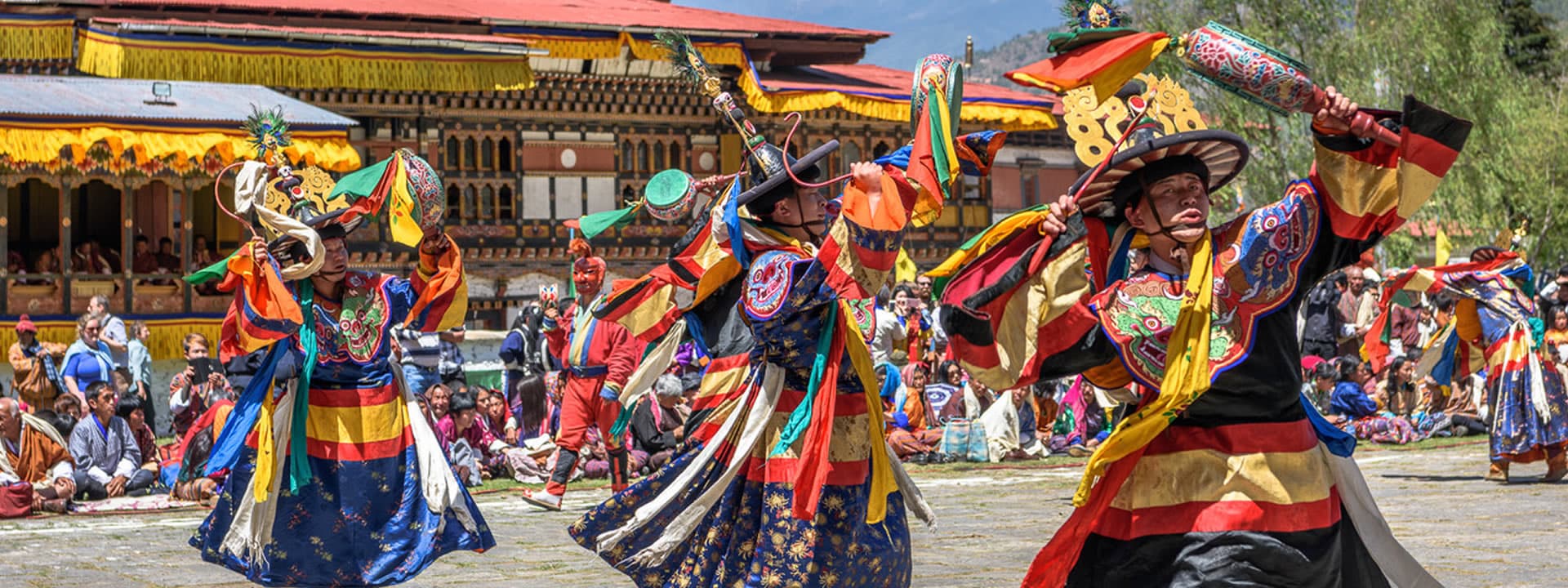 Black Hat dancers in swirling silk costumes performing at a tshechu festival