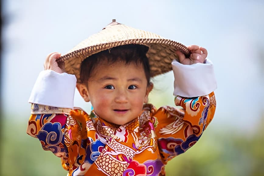 A smiling child wearing a traditional woven bamboo hat