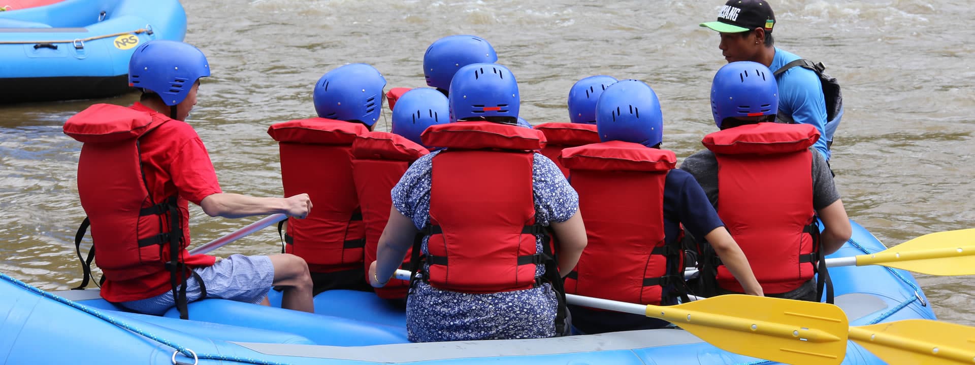 A rafting group in red life jackets and blue helmets on the Mo Chhu river